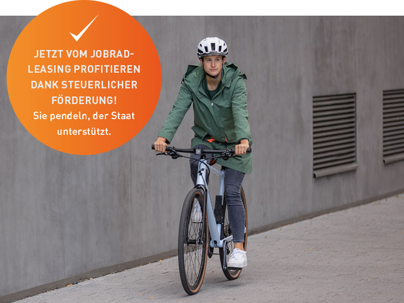 Ein Radfahrer mit grüner Parka-Jacke fährt auf einem Stadtrad durch eine graue Landschaft. Über dem Bild ist ein Button zu sehen. Aufschrift dessen ist: 